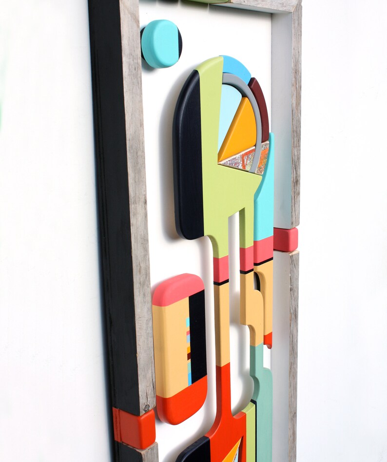 Puede incluir: Arte de pared geom&eacute;trico abstracto hecho de madera con una variedad de colores, incluyendo negro, blanco, rojo, naranja, amarillo, verde, azul y rosa. El arte est&aacute; enmarcado en un marco de madera r&uacute;stico.