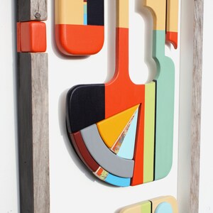 Puede incluir: Arte de pared geom&eacute;trico abstracto con un marco de madera. La obra de arte presenta una variedad de formas y colores, incluyendo rojo, naranja, amarillo, verde, azul y negro.