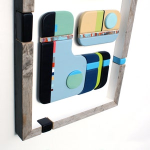 Puede incluir: Arte de pared geom&eacute;trico abstracto hecho de madera con un esquema de color azul, verde, amarillo y negro. El arte est&aacute; enmarcado en un marco de madera r&uacute;stico.