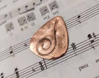 Custom guitar pick of upcycled hammered copper embossed with swirl symbol