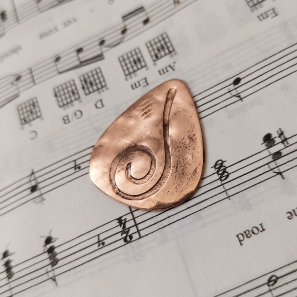 Custom guitar pick of upcycled hammered copper embossed with swirl symbol