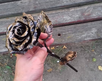 May include: A golden metal rose with black accents. The rose is crafted with intricate details and has a realistic appearance.
