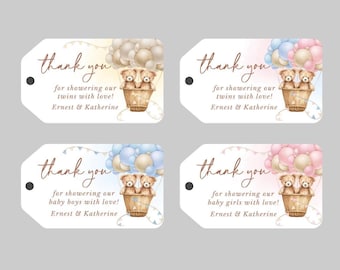 May include: Four thank you tags with a teddy bear hot air balloon design. The tags are for a baby shower and have different color schemes. One tag has a blue and white color scheme, one has a pink and white color scheme, and two have a beige and white color scheme. The text on the tags reads "Thank you for showering our twins with love! Ernest & Katherine" and "Thank you for showering our baby boys with love! Ernest & Katherine" and "Thank you for showering our baby girls with love! Ernest & Katherine".