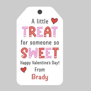 May include: A white gift tag with red and pink hearts and the text "A little TREAT for someone so SWEET Happy Valentine's Day! From Brady".