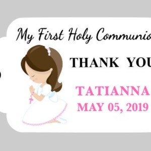 Puede incluir: Etiqueta de agradecimiento blanca con una ilustraci&oacute;n de dibujos animados de una ni&ntilde;a con un vestido blanco con una cinta rosa y cabello casta&ntilde;o. El texto en la etiqueta dice "My First Holy Communion", "Thank You", "Tatianna" y "May 05, 2019".