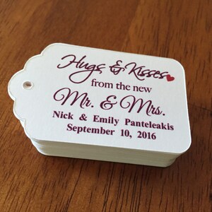 May include: White wedding favour tags with burgundy text that reads "Hugs & Kisses from the new Mr & Mrs Nick & Emily Panteleakis September 10, 2016".