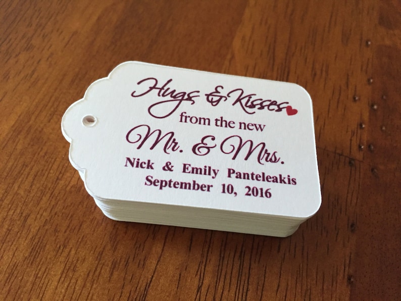 May include: White wedding favour tags with burgundy text that reads "Hugs & Kisses from the new Mr & Mrs Nick & Emily Panteleakis September 10, 2016".