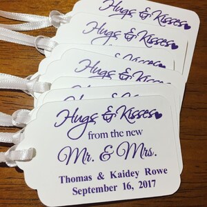 May include: White favour tags with purple text that reads "Hugs & Kisses from the new Mr. & Mrs. Thomas & Kaidey Rowe September 16, 2017".