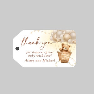 May include: Thank you for showering our baby with love! Aimee and Michael. A brown teddy bear sits in a hot air balloon with white and beige balloons. The balloon is surrounded by a yellow and white background with white bunting.