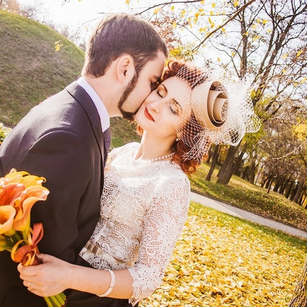 Chapéu fascinator bege para casamento com véu gaiola: acessório moderno para noiva