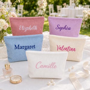 May include: Five rectangular corduroy pouches in pink, lavender, light blue, cream, and white. Each pouch features embroidered names: Elizabeth, Sophia, Margaret, Valentina, and Camille in matching or contrasting thread colours on the front.