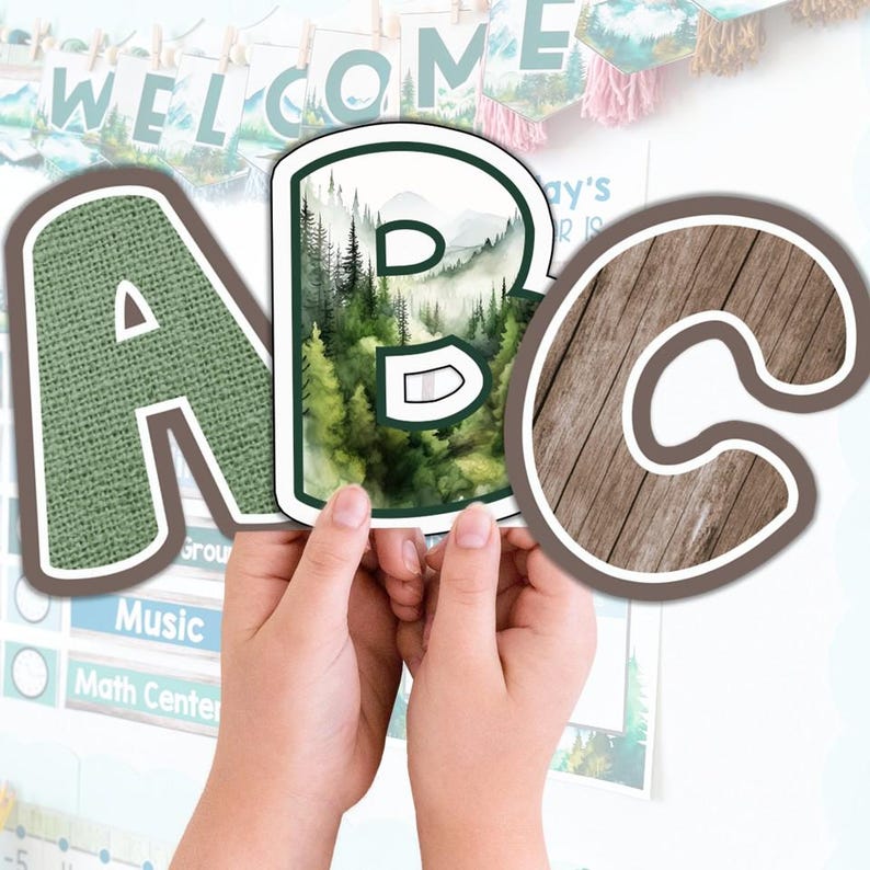 May include: A close-up of the letters A, B, and C. The letter A has a green burlap texture, the letter B features a watercolor forest scene, and the letter C has a wood grain texture. The letters are part of a classroom decoration.
