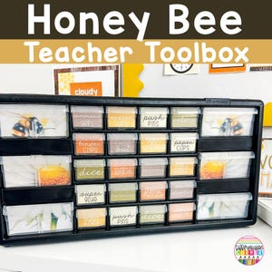 May include: A black plastic drawer organizer with clear drawers labeled with bee-themed designs and words like "push pins", "paper clips", "dice", and "super glue".