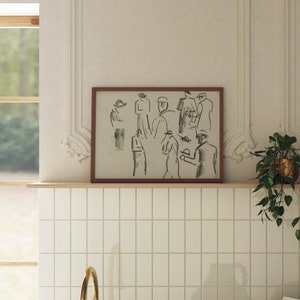 Op de afbeelding: Een ingelijste zwart-wit schets van mensen in een groep. De schets is in een bruin frame en hangt aan een witte betegelde muur.
