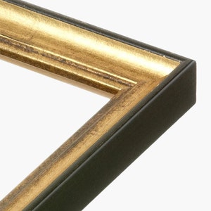 Puede incluir: Primer plano de un marco de imagen con un exterior de madera negra y un borde interior dorado.