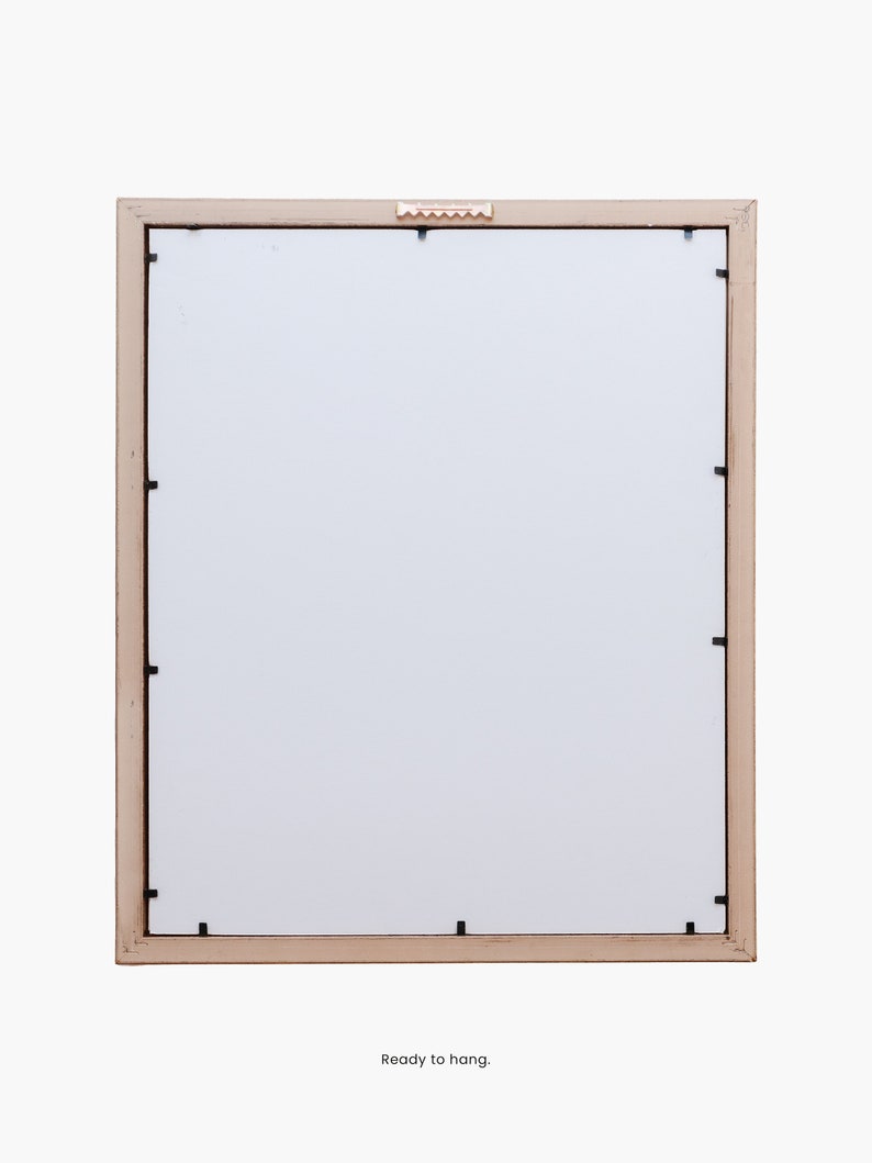Puede incluir: Un marco de fotos de madera marr&oacute;n claro con un paspart&uacute; blanco y un peque&ntilde;o gancho de colgar dorado en la parte superior. El marco est&aacute; listo para colgar.