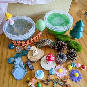 May include: A selection of miniature fairy garden accessories, including a small wooden bridge, a squirrel figurine, mushrooms, flowers, and a miniature waterfall. The set also includes two containers of green and black slime, and a wooden tree.