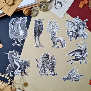 以下が含まれることがあります： グリフィン、スフィンクス、ミノタウロス、マーメイド、ケンタウロス、フェニックス、ドラゴン、フクロウ、ユニコーンなど、神話上の生き物を描いた白黒のイラスト9点セット。イラストは白い紙に印刷されており、ヴィンテージな雰囲気があります。