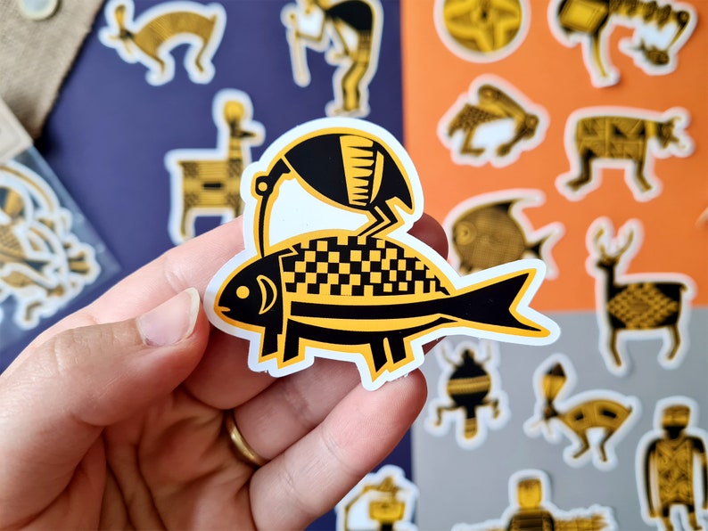 May include: A black and yellow sticker of a stylized fish with a bird perched on top. The fish has a checkered pattern and the bird has a rounded body and a long beak.