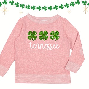 May include: Pink sweatshirt with three green glitter shamrocks and the word "Tennessee" in white.