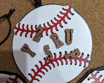 May include: A white baseball ornament with red stitching and brown wooden letters spelling "YZSRU".