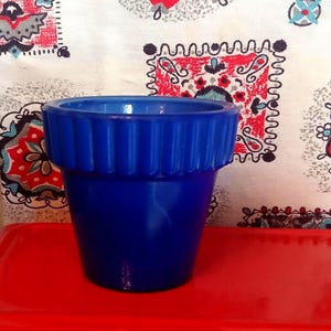 Op de afbeelding: Een levendige kobaltblauwe keramische plantenpot met een brede, geribbelde rand met verticale groeven. De pot heeft een gladde, glanzende afwerking en een taps toelopend lichaam dat smaller wordt naar de basis, wat zorgt voor een strakke vorm.
