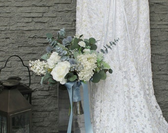 Dusty Blue Brides Boho wedding bouquet with Ivory roses and lilacs. Thistle eucalyptus and dusty miller.