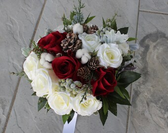 Winter Boho bouquet with White and Red roses, pine cones, evergreen and bay leaves. Grey Brunia berries and dusty miller.