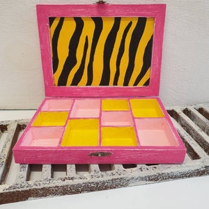 May include: Pink wooden box with a tiger print lid and yellow and pink compartments inside.