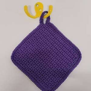 Peut inclure: Un porte-pot en crochet violet avec une anse en boucle suspendu à un crochet jaune.