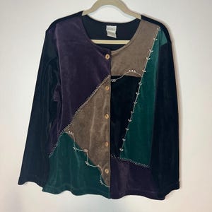 May include: A long-sleeved button-down shirt made of velvet fabric featuring a color-blocked design in shades of purple, brown, black, and dark green. The garment includes decorative white embroidered vine patterns along the diagonal seams.