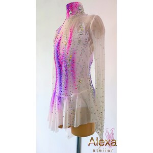 May include: White figure skating dress with long sleeves and a high neck. The dress has a pink and purple ombre design with rhinestones.