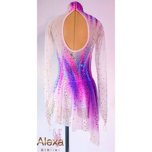 May include: White figure skating dress with a pink, purple, and blue ombre design. The dress has long sleeves and a keyhole back. The dress is decorated with rhinestones.