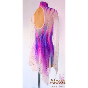 May include: A white, long-sleeved figure skating dress with a pink and purple ombre design and rhinestones. The dress has a keyhole back and a short, asymmetrical skirt.