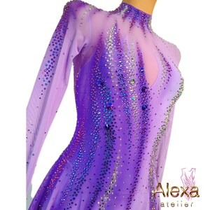 Pu&ograve; includere: Un abito da pattinaggio artistico di colore viola con maniche lunghe e collo alto. L'abito &egrave; decorato con strass iridescenti a forma di fiamma.