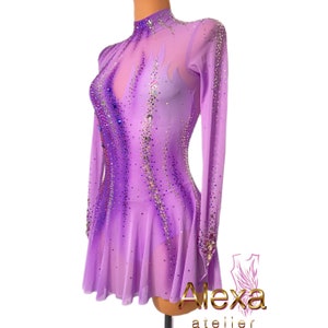Pu&ograve; includere: Un abito da pattinaggio artistico viola con un'overlay trasparente e un design a fiamma. L'abito &egrave; decorato con strass e ha maniche lunghe.