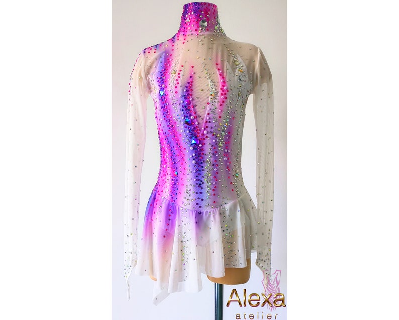 May include: A white figure skating dress with long sleeves and a pink, purple, and white ombre design. The dress is embellished with rhinestones.