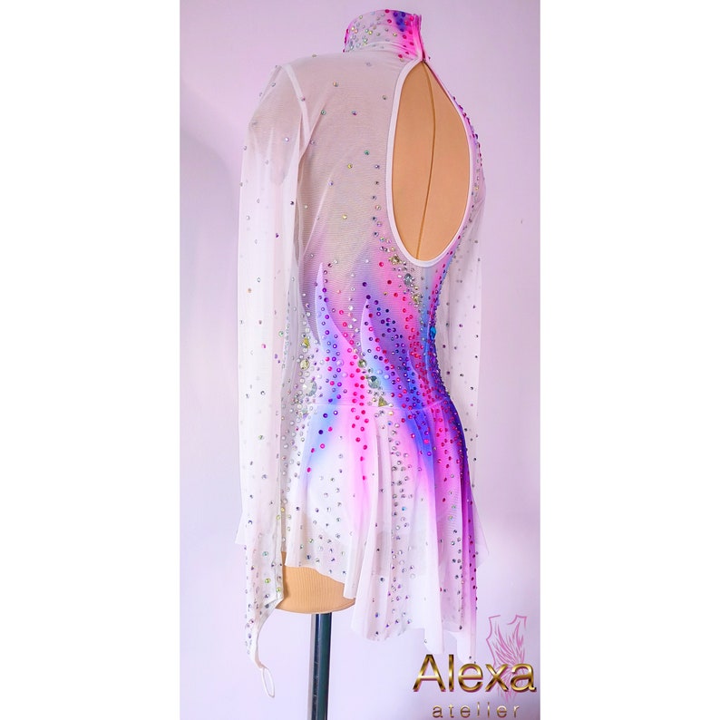 May include: White figure skating dress with long sleeves and a keyhole back. The dress has a pink, blue, and purple ombre design with rhinestones.