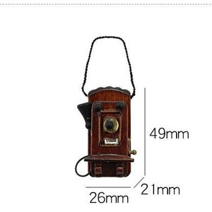Pu&ograve; includere: Un telefono a muro in legno in stile vintage con un ricevitore nero e un cavo marrone. Il telefono &egrave; alto 12,4 cm, largo 6,6 cm e profondo 5,3 cm.