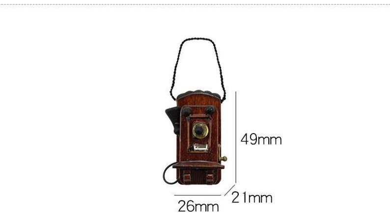 Pu&ograve; includere: Un telefono a muro in legno in stile vintage con un ricevitore nero e un cavo marrone. Il telefono &egrave; alto 12,4 cm, largo 6,6 cm e profondo 5,3 cm.