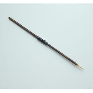 May include: A wooden stick with a dark brown finish and a light brown tip. The stick has a band of dark blue material wrapped around it.