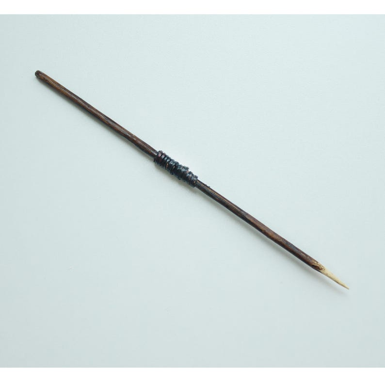 May include: A wooden stick with a dark brown finish and a light brown tip. The stick has a band of dark blue material wrapped around it.