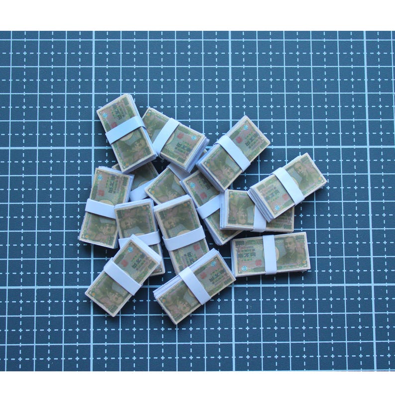 May include: A collection of miniature stacks of paper currency, each secured with a white band. The bills feature a portrait and text, arranged on a blue grid surface.