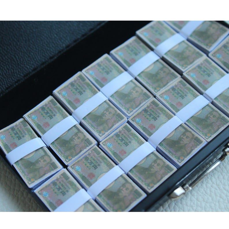 May include: Stacks of Japanese Yen banknotes, each secured with a white paper band. The banknotes are arranged neatly inside a black case. The bills feature a portrait and Japanese text.
