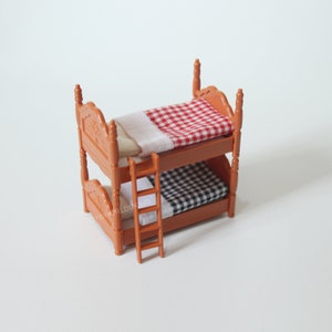 May include: A wooden bunk bed with a red and white checked blanket on the top bunk and a black and white checked blanket on the bottom bunk. The bed has a ladder on the side.