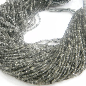 May include: A strand of gray gemstone beads, approximately 2 mm in diameter, strung on a thin cord. The beads are faceted and have a translucent appearance.