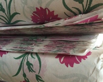 Puede incluir: Rollos de tela blanca con estampado floral rosa y verde. La tela está apilada una encima de la otra.