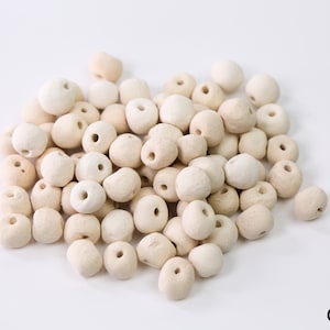 May include: A pile of off-white ceramic beads with a hole in the center of each bead.