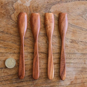 Puede incluir: Cuatro cuchillos de mantequilla de madera con bordes redondeados y un acabado de madera natural.