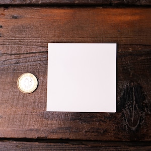 May include: A white square card mockup on a brown wooden surface with a gold coin.
